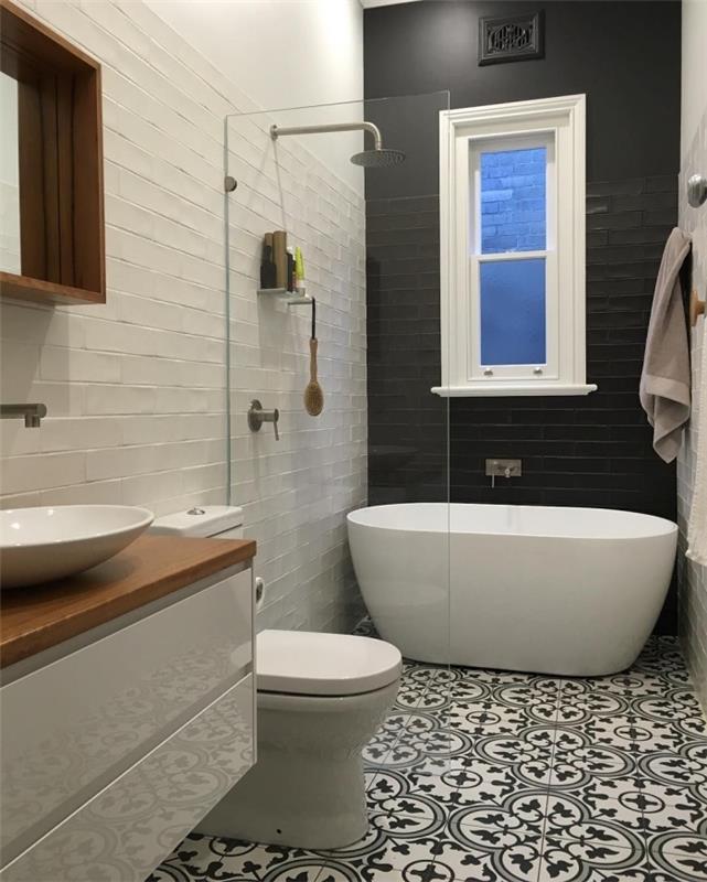 juodos ir baltos cemento plytelės su įvairaus dydžio arabesko raštais, atitinkančiomis elegantišką juodai balto vonios kambario atmosferą, atspindinčią blizgančio ir matinio sienų ir baldų efektą