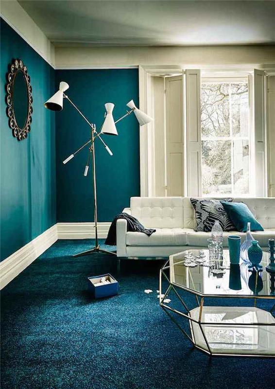 anties mėlyna apdaila su balta sofa ir benzino mėlynu kilimu, balta dizainerio grindų lempa ir dizainerio stiklo stalas