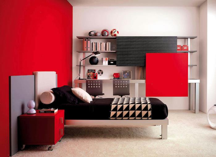 rdeče -črni dekor, rdeča naglasna stena in nočna omarica z rdečimi predali, postelja iz nerjavečega jekla, črna žimnica in blazine, preprosta polica za knjige, bela preproga