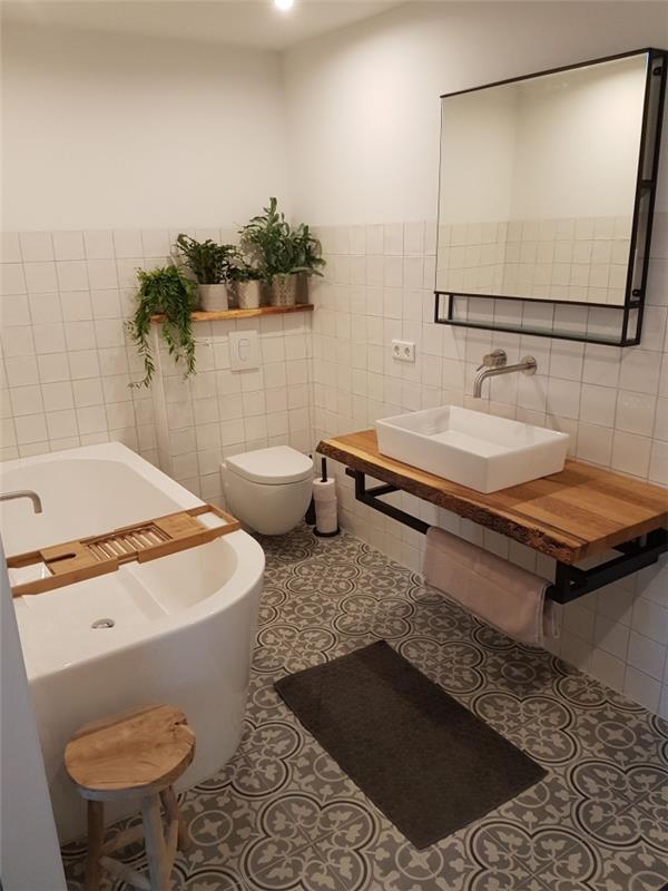 vonios kambarys su cemento plytelėmis su dideliais arabesko raštais, suteikiančiais rafinuotą šio vonios kambario atmosferą su vonia su pramoniniais akcentais