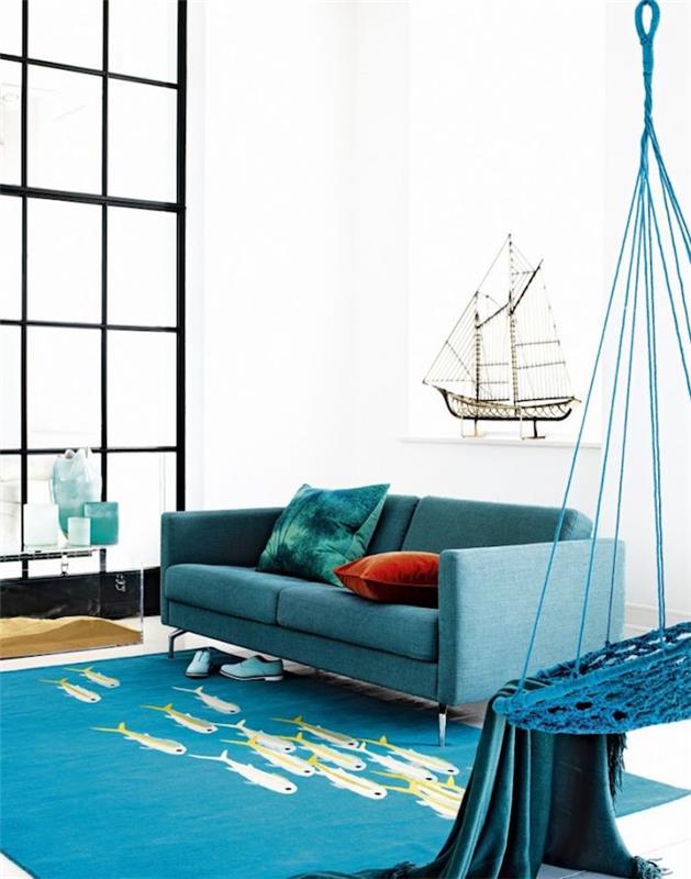 svetainės apdaila jūros tema, povo mėlyna sofa ant kilimo su žuvimi ir balta siena