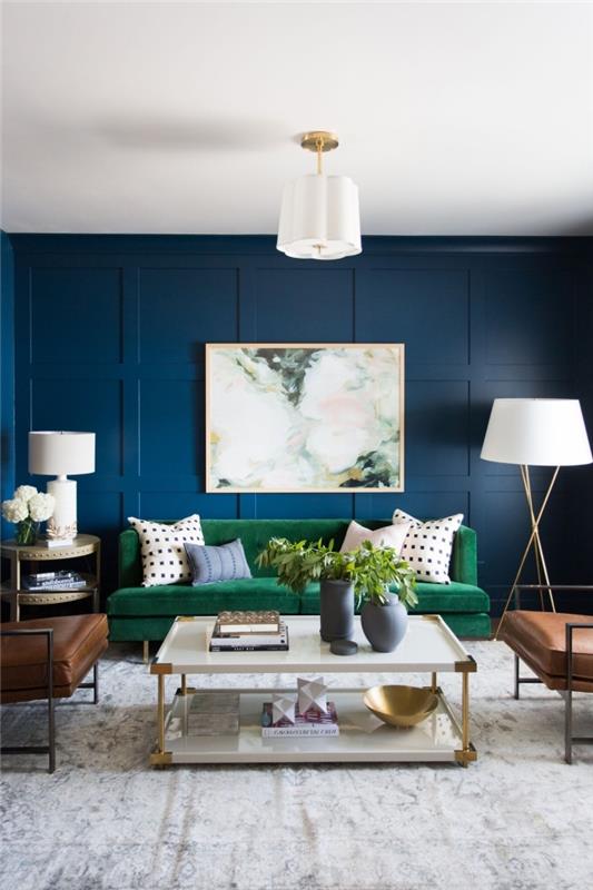 Mermer efektli bir tablo ve yeşil kanepe ile zenginleştirilmiş koyu mavi arka plan, küçük oturma odasına derinlik katıyor.