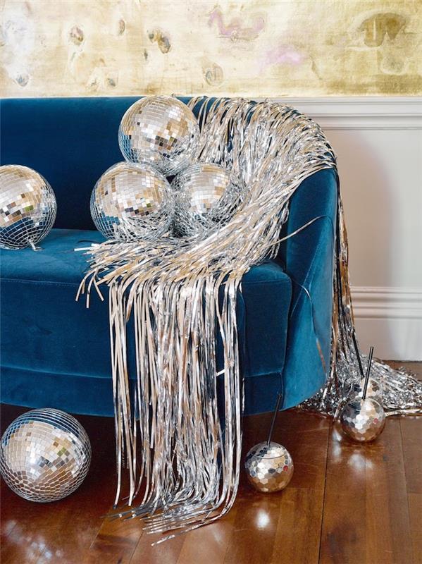 srebrne girlande in zrcalne kroglice na račjem modrem kavču v čarobni dnevni sobi, okrašeni za novo leto