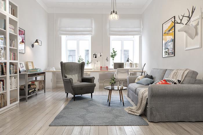 dekoriranje deco s kavčem, naslanjačem in sivo preprogo, parket iz svetlega lesa, bela stena, knjižna omara, lovska trofeja