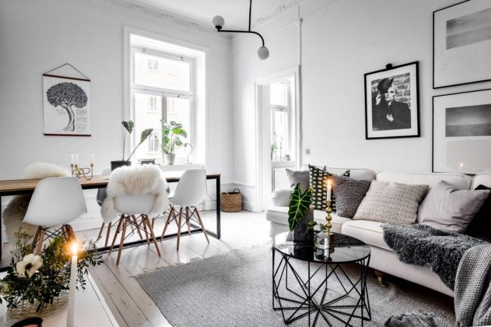 sivo-beli dekor dnevne sobe s sivobelim kavčem, sivimi, črno-belimi blazinami, oblikovalsko črno mizo za kavo, leseno in kovinsko mizo ter skandinavskimi stoli, krzno