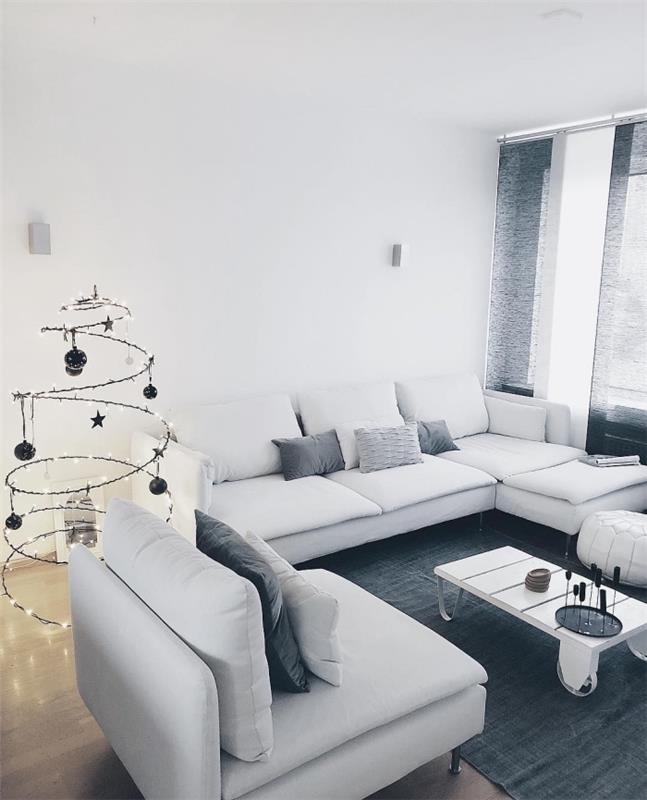 deko pilka ir balta monochrominė ir rafinuota svetainė su ryškia spiraline Kalėdų eglute ir pramoniniu kavos staliuku baltame padėkle