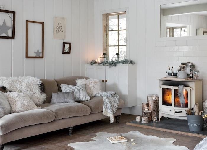 kmečko -siva in bela dekoracija dnevne sobe, starinski kamin, siv kavč, krzno, krzno in pletene prevleke za blazine, leseni parket, belo opaž