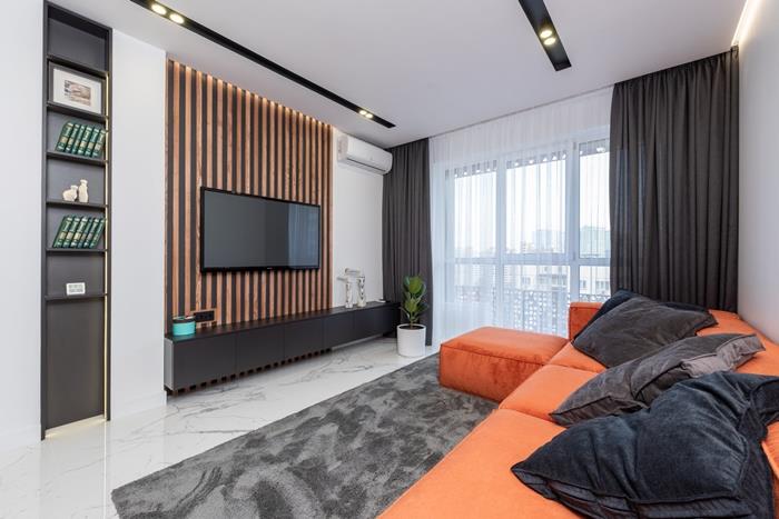 gri halı oturma odası dekoru turuncu köşe kanepe uzun koyu perdeler beyaz duvar led aydınlatma siyah mobilya