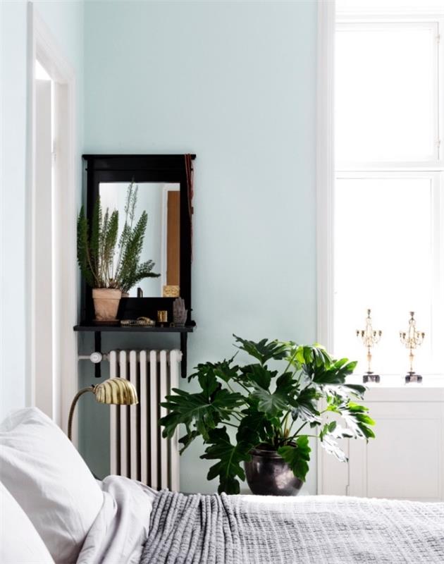 Açık mavi, beyaz ve gri nevresimler, yeşil bitki, eski ayna ile yeniden boyanmış İskandinav yatak odası dekoru