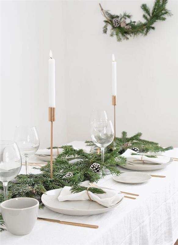 İskandinav Noel masa dekorasyonu, altın mumlar, altın çatal bıçak takımı oluşturmak için kar efektli çam dalları ve çam kozalakları