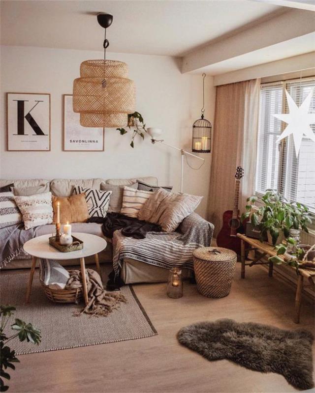 Prabangi skandinaviška svetainė su sofa, perkrauta antklodėmis ir pagalvėlėmis ant šviesaus medžio parketo augalų ant stalo langų kabančių žvaigždžių