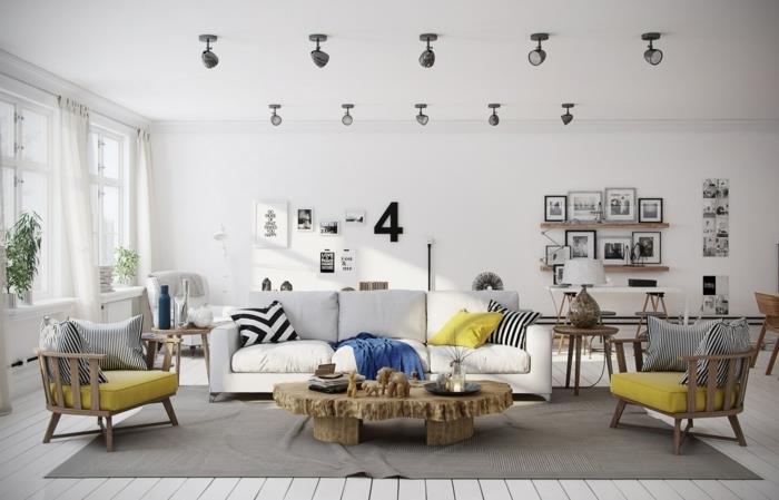 Gri ve beyaz İskandinav oturma odası dekoru, sarı sandalye minderi vurguları, mavi battaniye, beyaz kanepe, rustik masa, siyah beyaz fotoğraf duvar dekoru