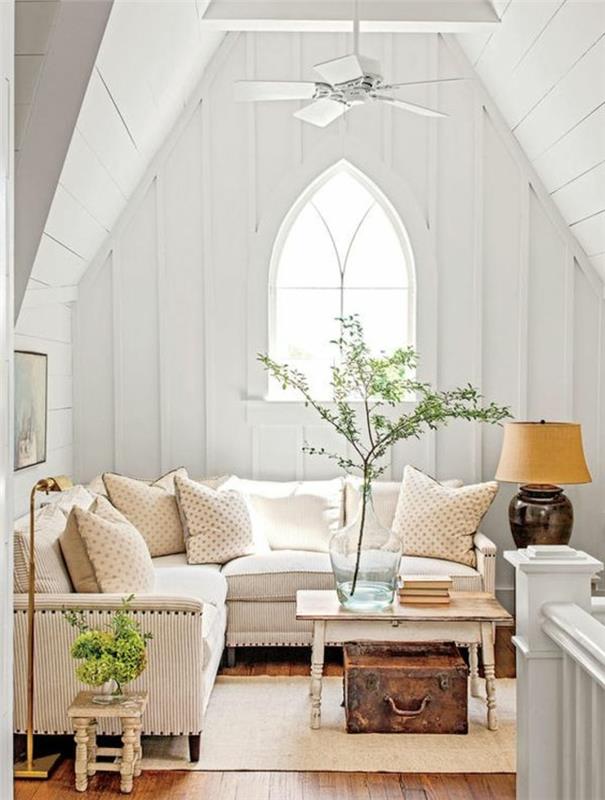eleganten deželni dekor dnevne sobe, kavč z belimi črtami, majhna klubska mizica, veje, pokrite z zelenimi listi, starinska skrinja, stena, beli strop