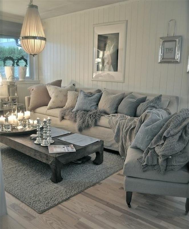 eleganten podeželski dekor, lesena tla, siv kavč in naslanjač, ​​originalna viseča svetilka, siva lesena mizica, modre, bele in sive blazine, svečniki in sveče