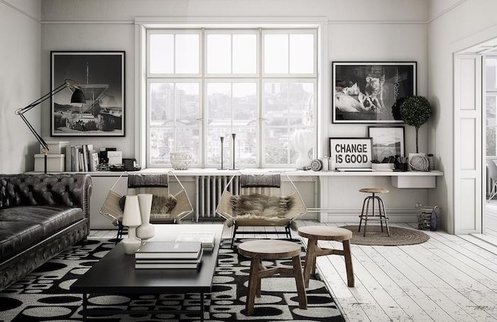 industrijska dekoracija skandinavska dnevna soba s črnim kavčem, črna mizica, siva in črna preproga, leseni stolčki, stol z živalsko kožo, grafična dekoracija črno -belih slik, pobeljen parket