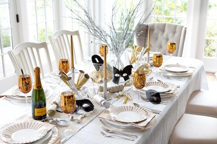 kozarci za šampanjec v zlati barvi, črne pustne maske, konfetski top, deko, osrednja veja, elegantna tema pustne zabave