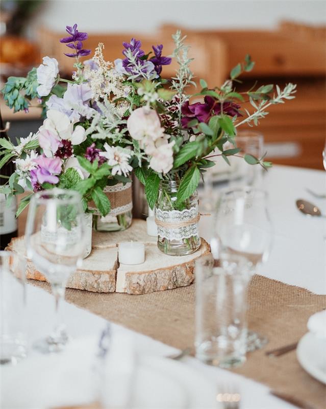 okrasitev poročne mize s tekačem za mizo, lesena podložka s steklenimi kozarci s šopki rož in čipk, juta in okras