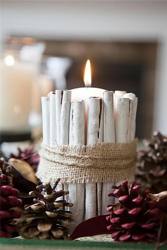 Kalėdinis papuošimas, kad pasidarytumėte lengvas, didelė balta žvakė su cinamono lazdelėmis, nudažyta baltais dažais, aplink - raudonos spalvos kankorėžiai, Kalėdų centras