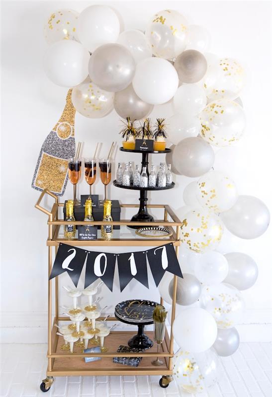 orijinal dekoratif aksan, bardaklar, şampanya şişeleri ile altın renkli bir büfenin etrafındaki beyaz ve altın balon kemeri