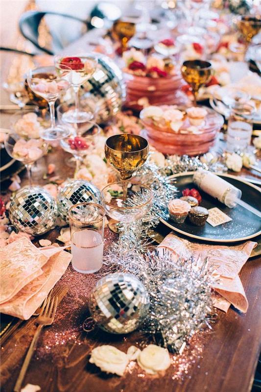 deco st sylvestre eve miza s sijočimi elementi in disko kroglicami zlati jedilni pribor in kozarci na leseni mizi