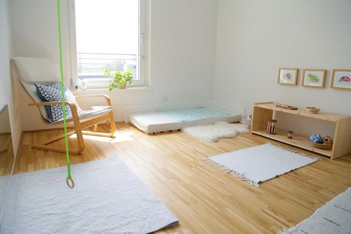 blaivus ir rafinuotas kambarys Montessori atmosferai, šviesaus medžio parketas, aktyvumo kilimėlis, baltas čiužinys, lentynos