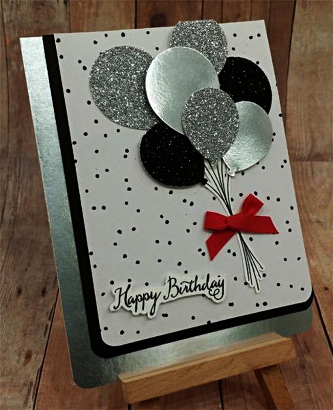 lepa rojstnodnevna voščilnica v beli in črni barvi na kovinskem podstavku iz papirja, okrašena z reliefnimi baloni v srebrnem in bleščečem papirju