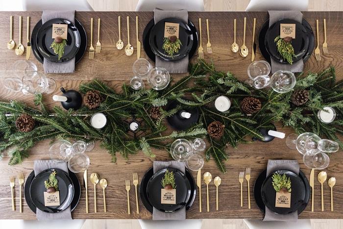 Božična miza osrednja dekoracija v jelkovih vejah bele sveče temna lesena miza naravni materiali