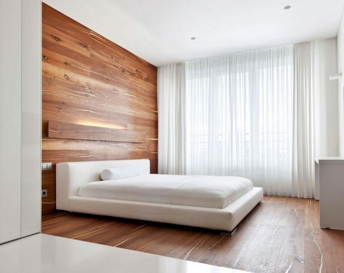 minimalistiniu stiliumi įrengtas suaugusiųjų miegamasis su baltomis sienomis su grindų danga ir rudomis sienų dailylentėmis