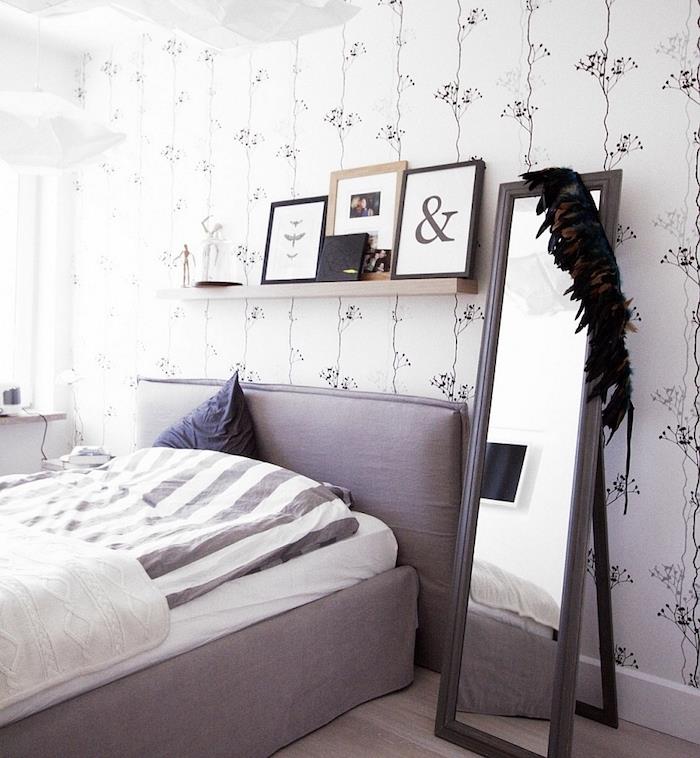 yetişkin yatak odası duvar kağıdı, beyaz bir dalga üzerinde zarif çiçek desenleri, gri yatak, gri ve beyaz nevresimler, dikdörtgen ayna, dekoratif çerçeveler