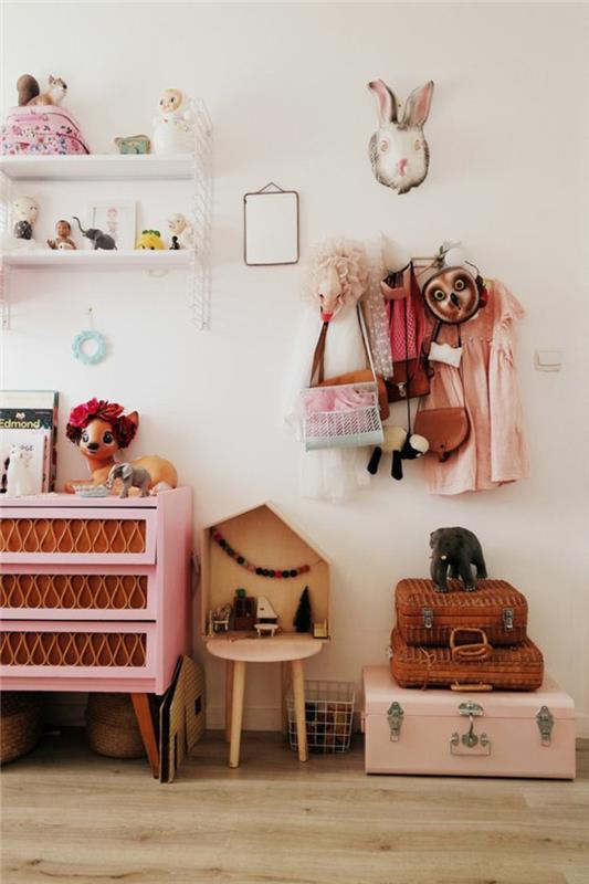 rožinis ir pilkas miegamasis, rožiniai ir rudi baldai, rožinis lagaminas ir du mažesni rudi valsai, smėlio spalvos parketas