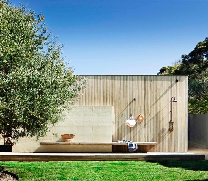 Peyzajlı bahçe düzeni, metal duşlu ve havlular için duvarlara tutturulmuş kancalı dış mekan banyosu modeli