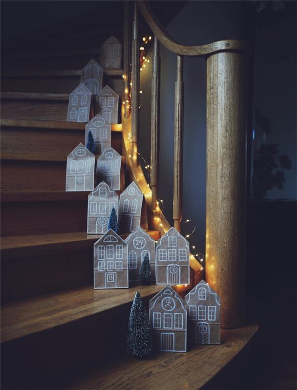 Ahşap korkuluklar boyunca merdiven basamaklarına yerleştirilmiş geri dönüştürülmüş kraft kollu Noel evleri, geri dönüştürülmüş kağıttan Noel dekorasyonu