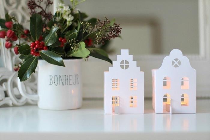 du šviesūs namai, iškirpti iš popieriaus, kad papuoštų stalą ar lentyną Kalėdoms, pasidarykite kalėdines dekoracijas su naminiais žvakidėmis