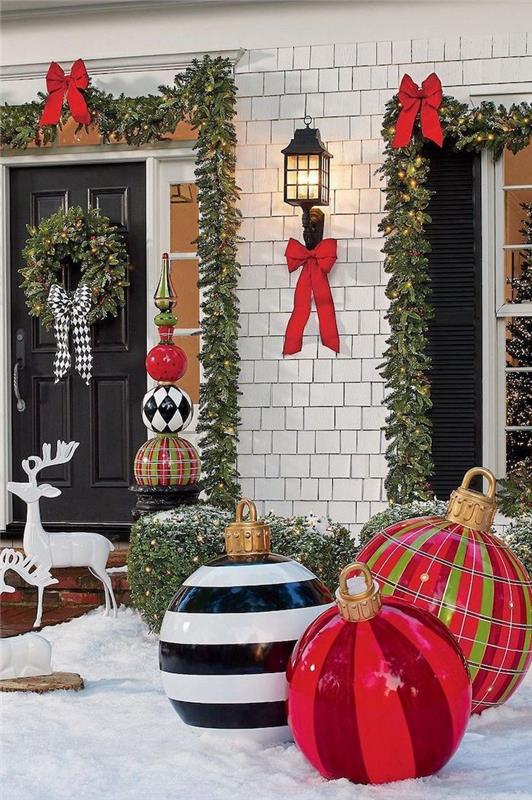lauko Kalėdų puošmena su didžiuliais kamuoliais priešais namą girliandos aplink langus ir dekoratyviniai elniai