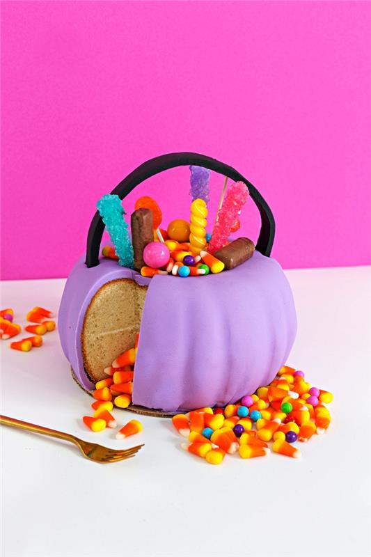 moliūgų formos Helovino pyragas su purpurinės cukraus pastos glajumi, papuoštas Helovino saldainiais