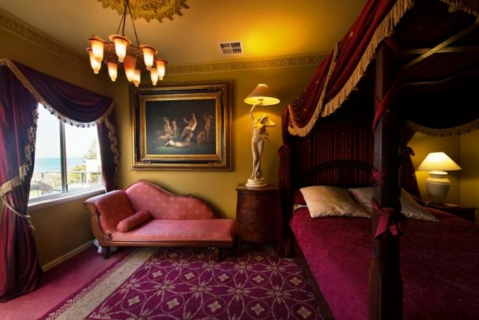 boudoir spalnica, vijolična postelja, vijolično ohišje z zlatimi obrobami, rumena nočna svetilka, velika slika