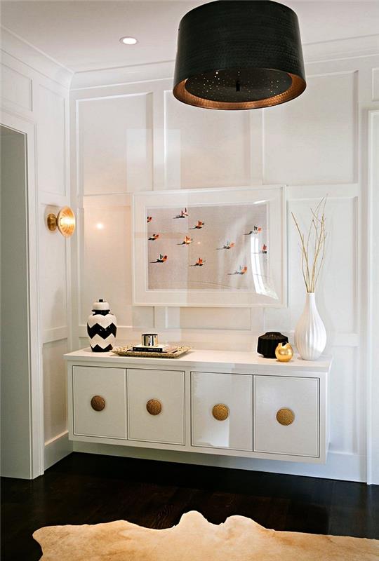 predsoba s črnim podom in belo plavajočo omarico z zlatimi poudarki, pritrjenimi na steno v beli leseni plošči