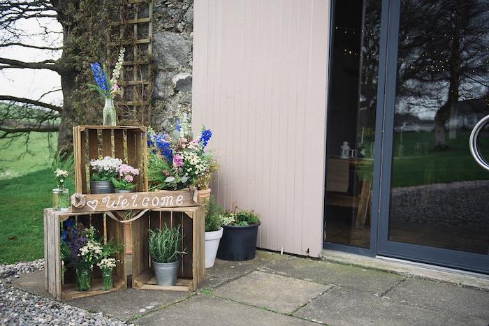 rustikalna poročna ideja v lesenem zaboju s cvetličnimi vedri ter steklenimi kozarci in steklenicami, napolnjenimi s cvetjem