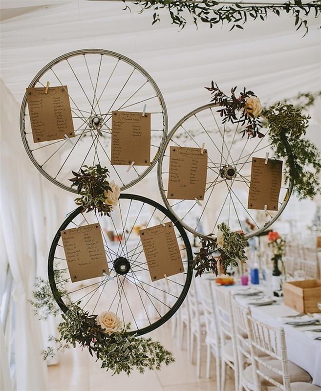rustik şık düğün dekorasyonu, çiçek süslemeli bisiklet tekerleklerinde orijinal masa planı, yeşil dallar, güller