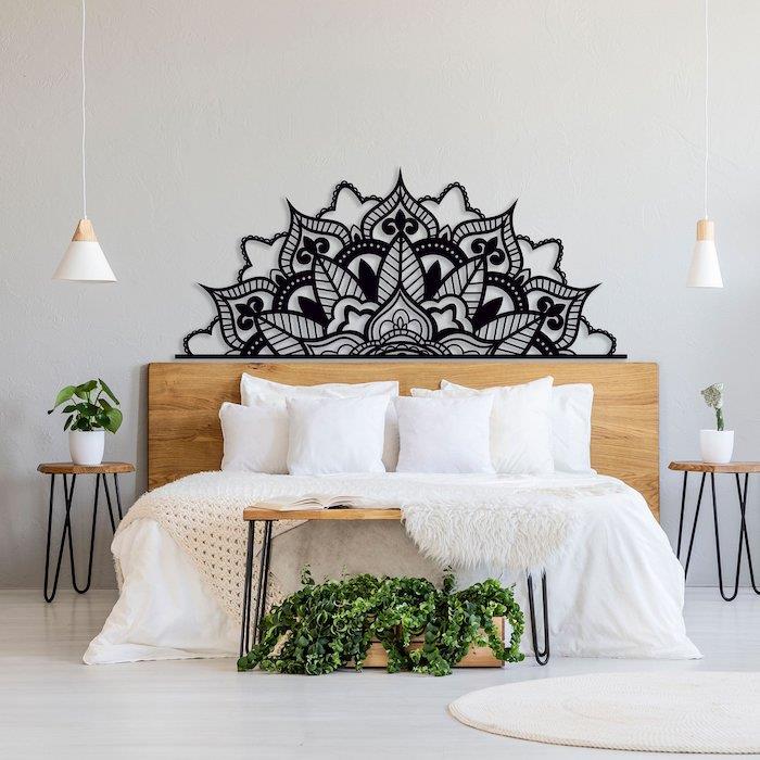 juodos mandalos sienų apdaila virš lovos tarp dviejų augalų, metalinė sienų apdaila