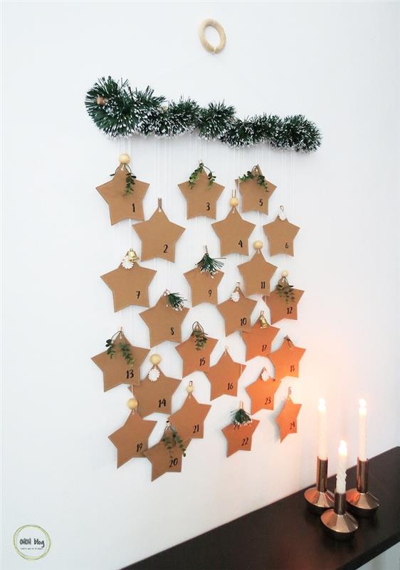 Advento kalendorius dirbtinėje pušies šakoje su kraftpopieriaus žvaigždėmis, pakabintomis kaip kalėdinė sienų puošmena