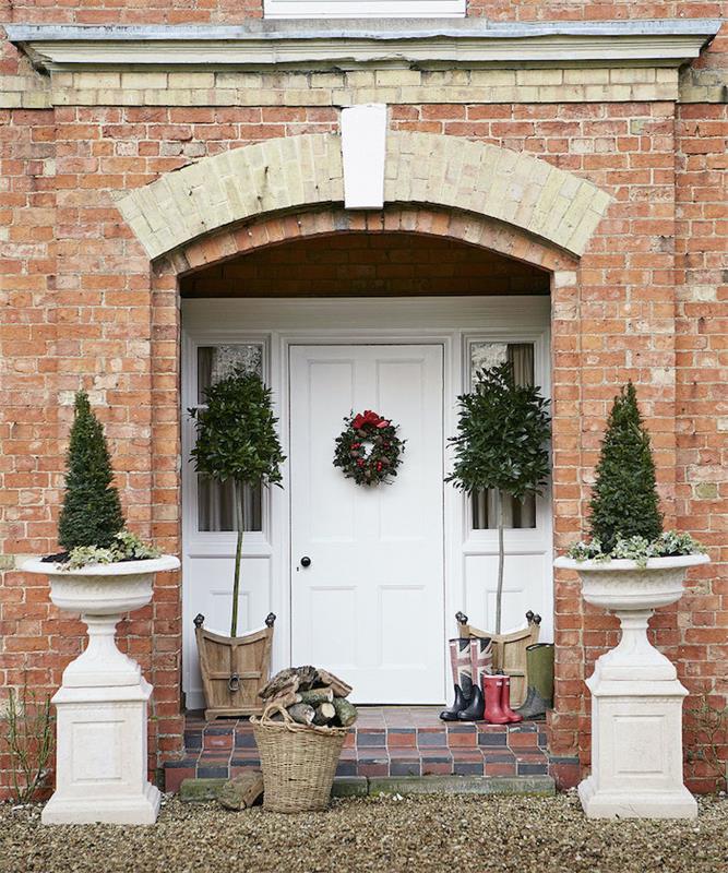 simetriška lauko Kalėdų puošmena su dviem krūmais urnose įrėmina duris