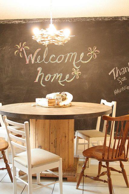 yemek odası dekor fikri, ham ahşap makaralı masa, ahşap sandalyeler, tahta duvar, ilginç avize, vintage şık atmosfer
