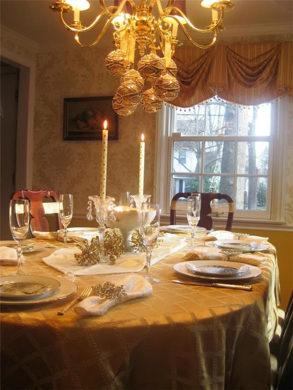 okrasitev mize na sveti večer s toplo svetlobo in zlatimi detajli ter okraski