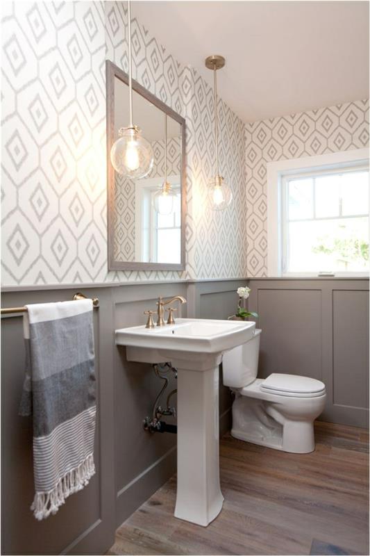 dizainerio tualetas pilkos ir baltos spalvos, pjedestalinis baseinas, medinės grindys, pakabinami šviestuvai, geometriniai tapetai, pilkas pagrindas