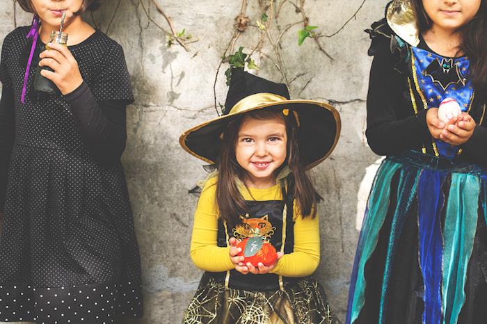cadı kostümü sarı bluzlu küçük kız, örümcek ağı desenli etek, geleneksel cadı şapkası capeline