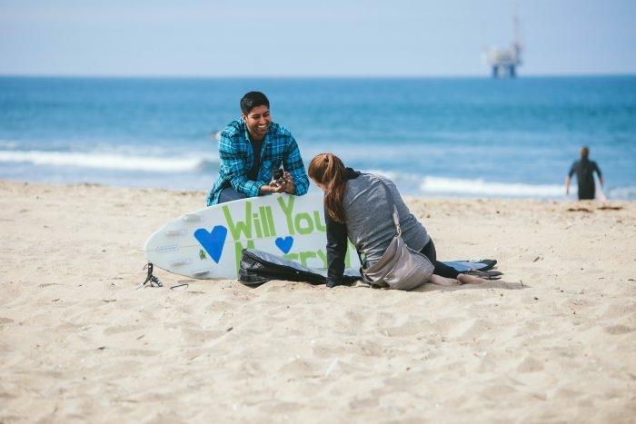ideja za presenečenje punca, sporočilo za poroko napisano na deski, predlog za poroko na plaži
