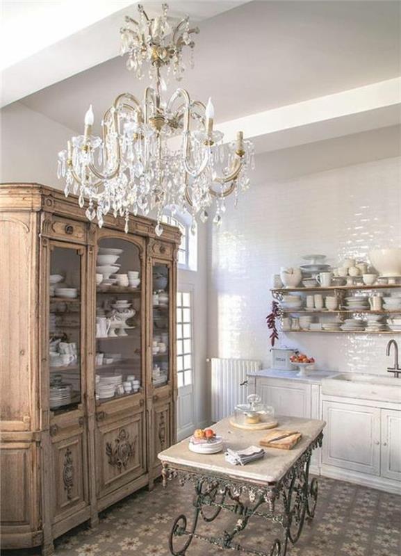 elegantna podeželska kuhinja, starinski leseni predalnik, eleganten lestenec, miza, kovinske noge, lesena polica, belo posodo, ploščice iz mozaika s cvetličnimi vzorci