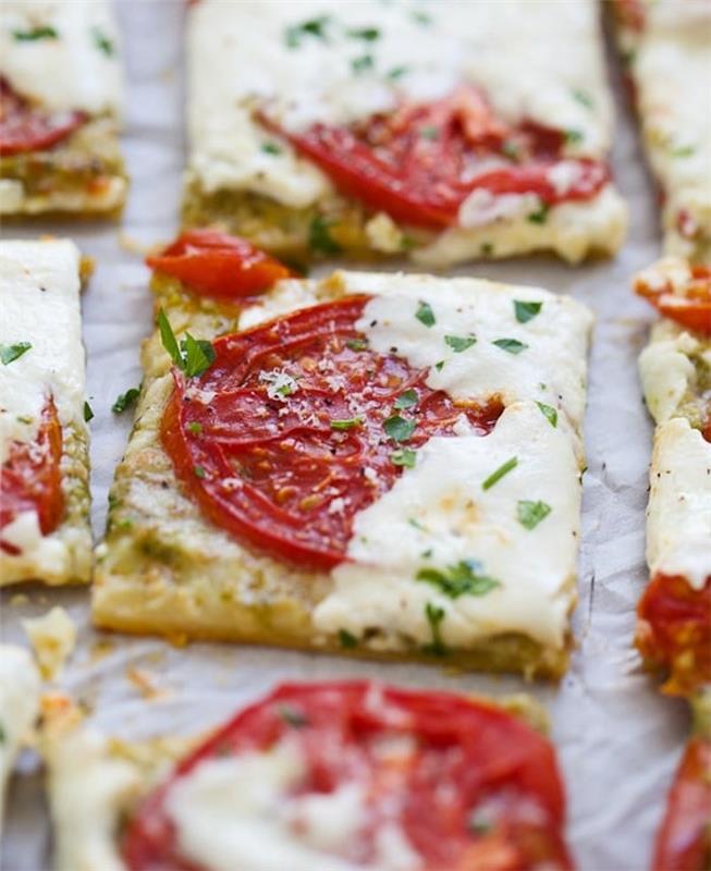 kolay fikir akşam yemeği aperitifi, üzerinde domates dilimleri, peynir ve kıyılmış maydanoz bulunan puf böreği kareleri