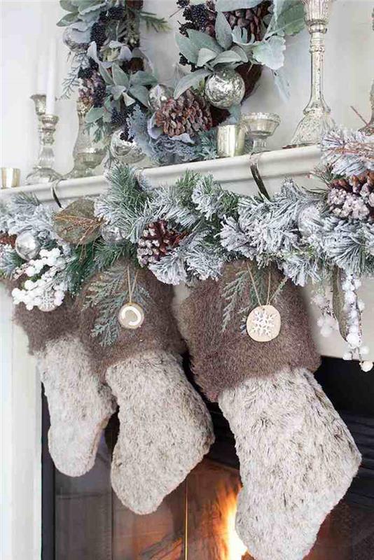 çelenkler ve sahte kar serpiştirilmiş çam kozalakları ile şömineden asılı örme çoraplar